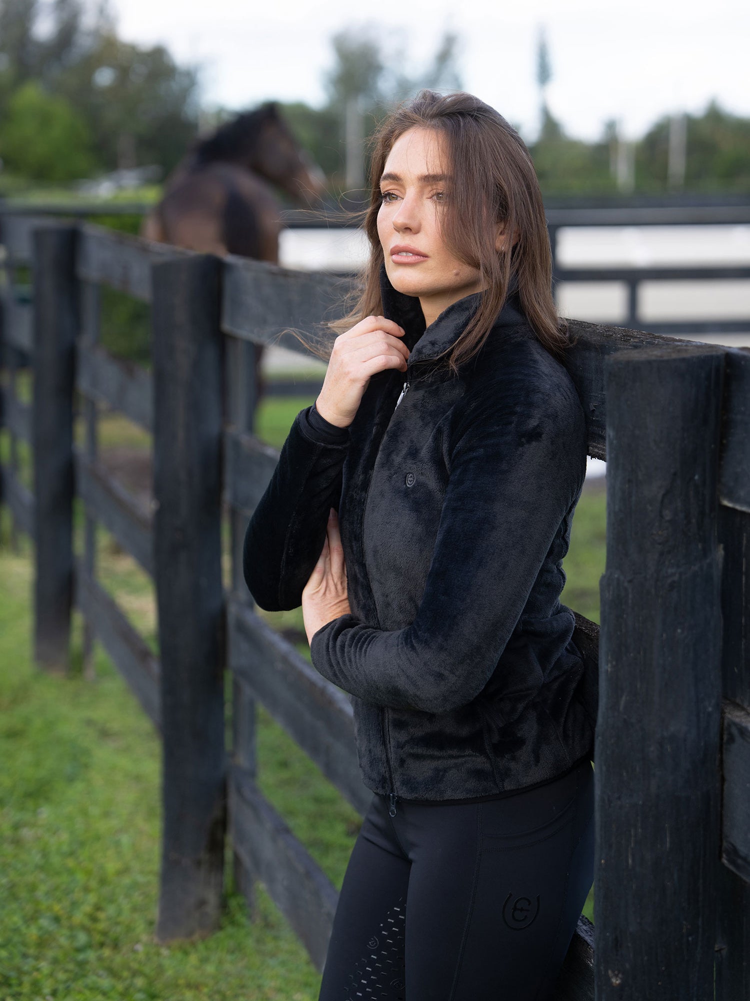 Cavalière portant la Veste Polaire Velvet Black Equestrian Stockholm dans une écurie extérieure.
