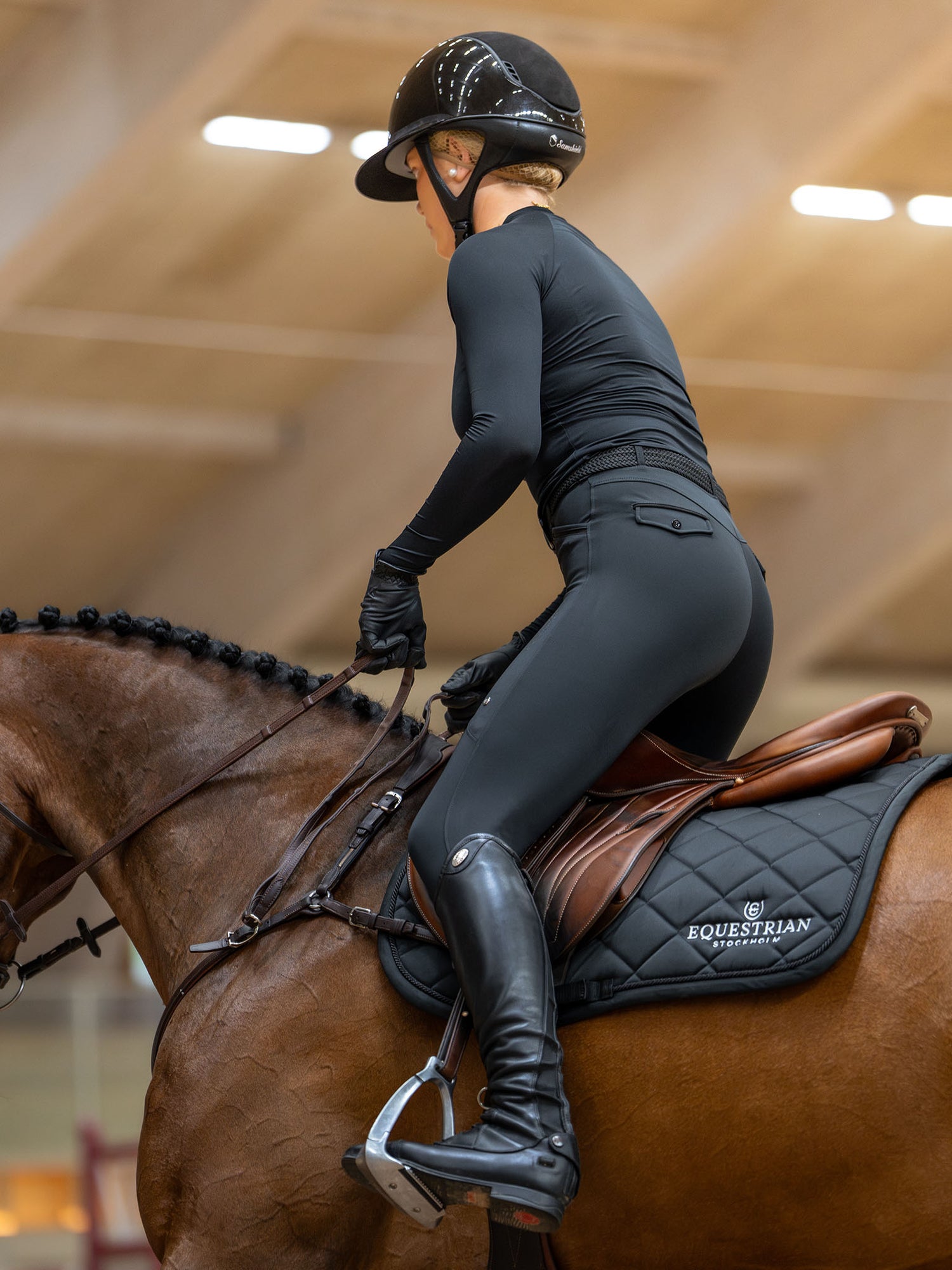 Rider in black gear on a brown horse featuring the Equestrian Stockholm Jump Saddle Pad Line Black with white embroidery.