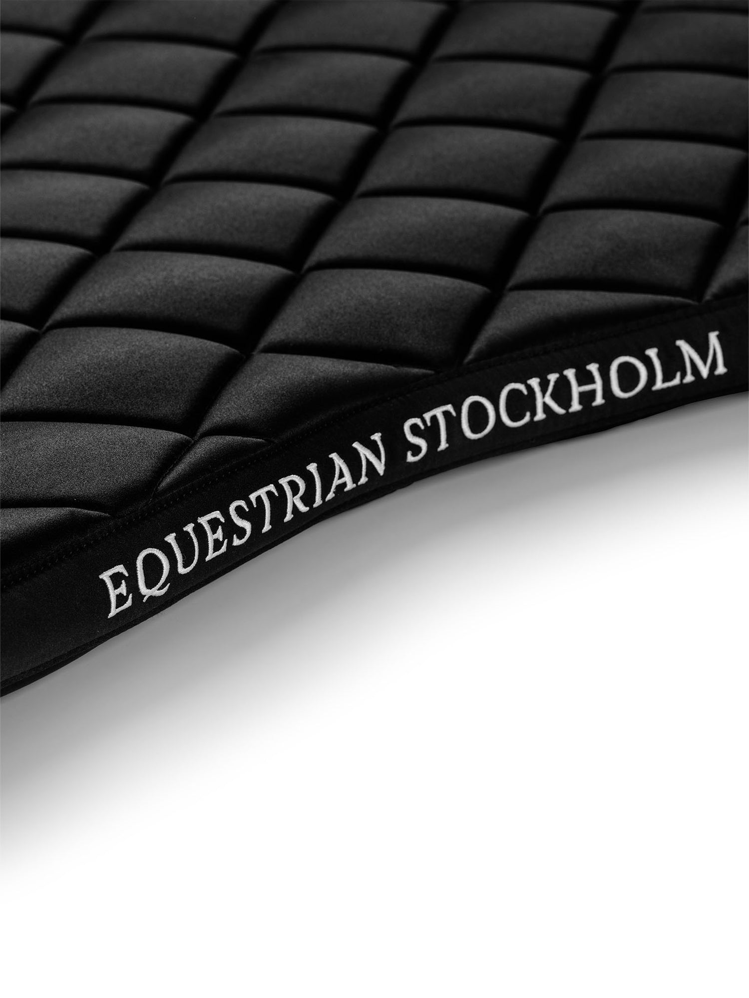 Studio image of Equestrian Stockholm Jump Saddle Pad Line Black with white logo embroidery and line quilting.