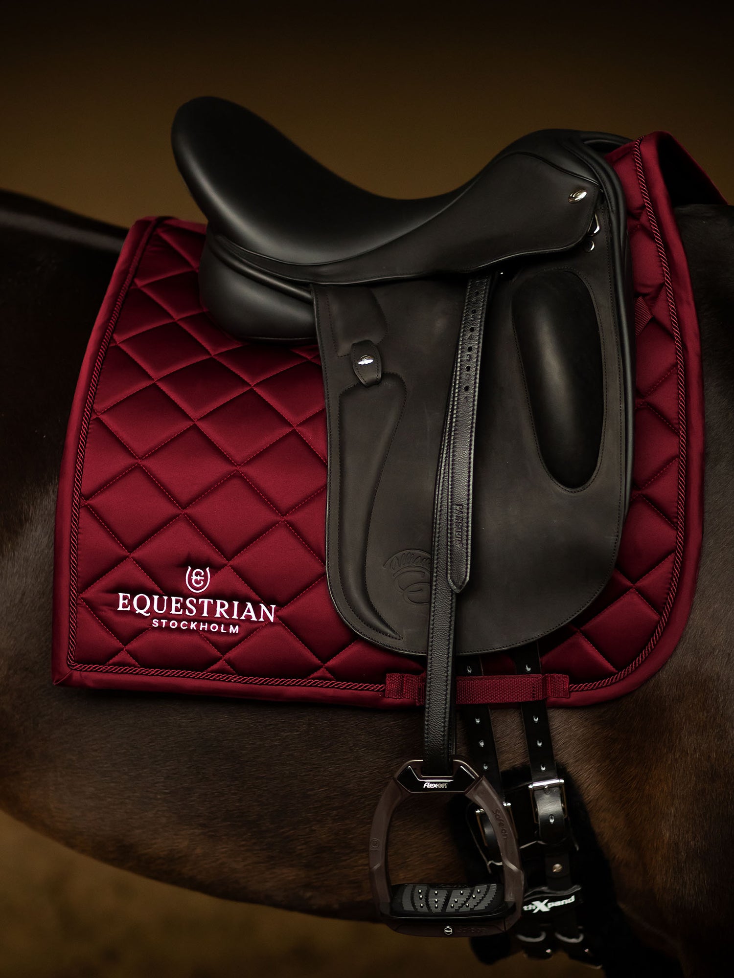 Studio image of Equestrian Stockholm Dressage Saddle Pad Line Bordeaux in deep red under a black saddle on a dark horse.