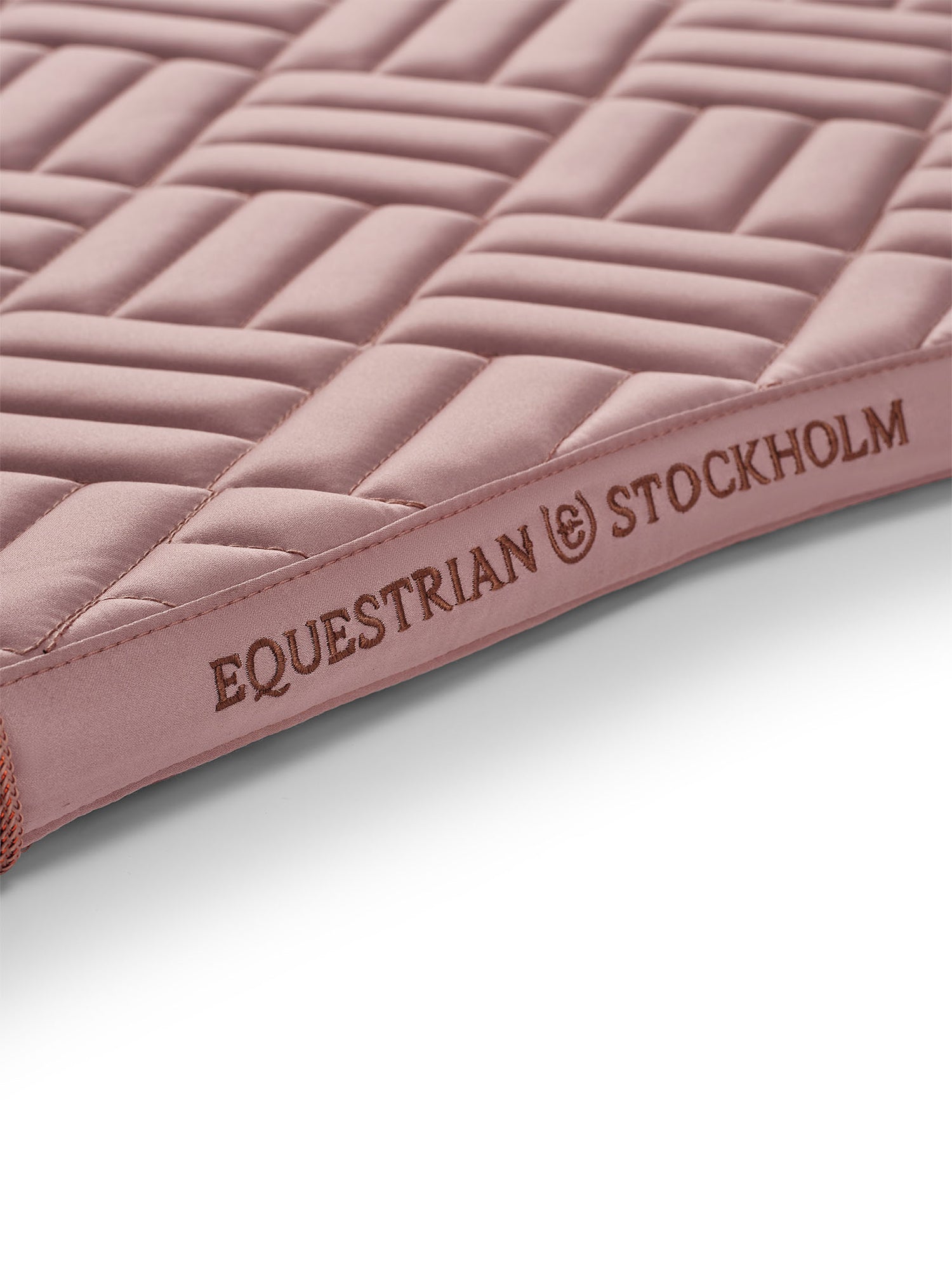 Studio image of Equestrian Stockholm sottosella da dressage Modern Midsummer Blush con logo oro rosa e trapuntatura moderna.