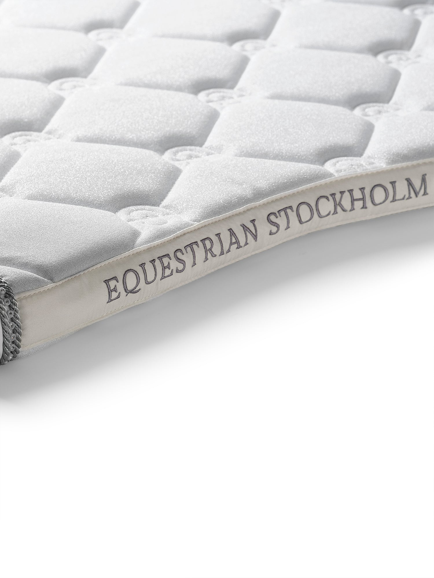 Studioaufnahme der Equestrian Stockholm Schabracke Crystal White Glimmer mit classic Steppung und Logo-Stickerei.