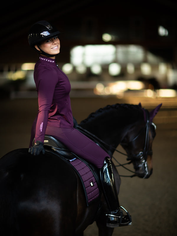 Model auf einem Pferd in Equestrian Stockholm Reitleggings Movement und passendem Top in Black Raven.