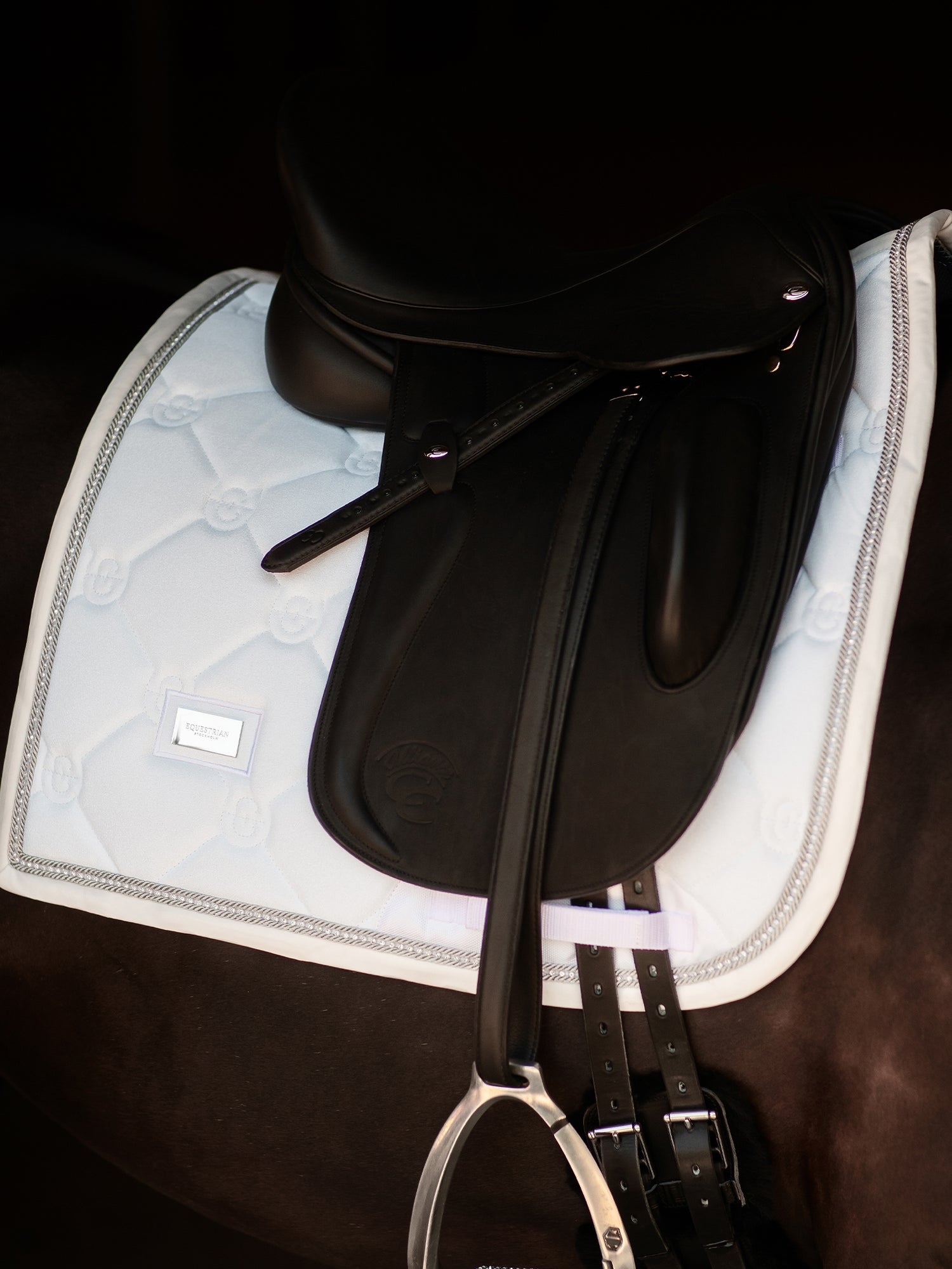 Equestrian Stockholm Dressage Saddle Pad Crystal White Glimmer under a black saddle with a silver stirrup on a horse.