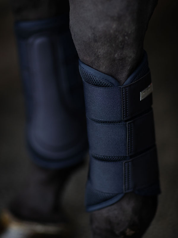 Studioaufnahme von Equestrian Stockholm Mesh Gamaschen Midnight Blue mit 3D-Mesh und silbernem Abzeichen am Pferd.