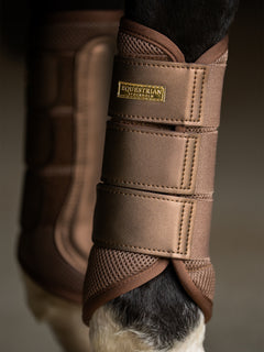 Immagine in studio delle stinchiere Mesh Equestrian Stockholm Champagne con badge oro e mesh 3D su gambe del cavallo.
