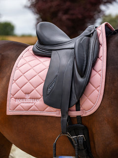 Equestrian Stockholm dressurunderlag Line Pink med diamantquiltning under en sort lædersadel på en hest.