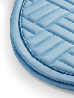 Studio image of Equestrian Stockholm Jump Saddle Pad Modern Midsummer Blue with modern quilting and silver piping.
