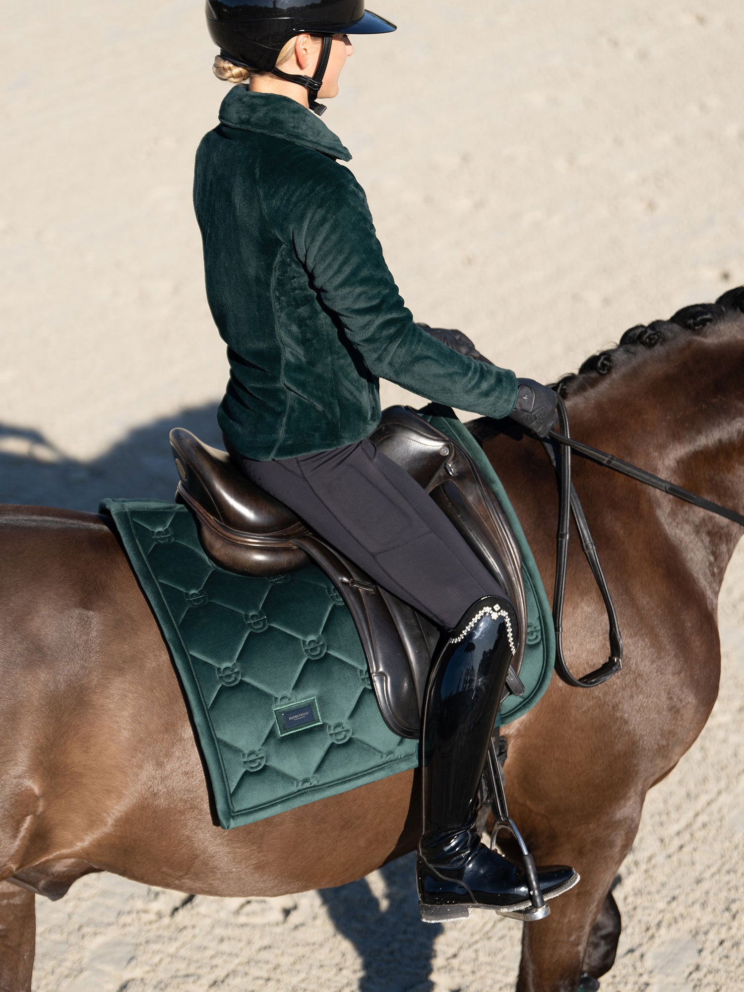 Rider on a brown horse wearing Equestrian Stockholm Sycamore Green velvet dressage saddle pad and matching fleece jacket.