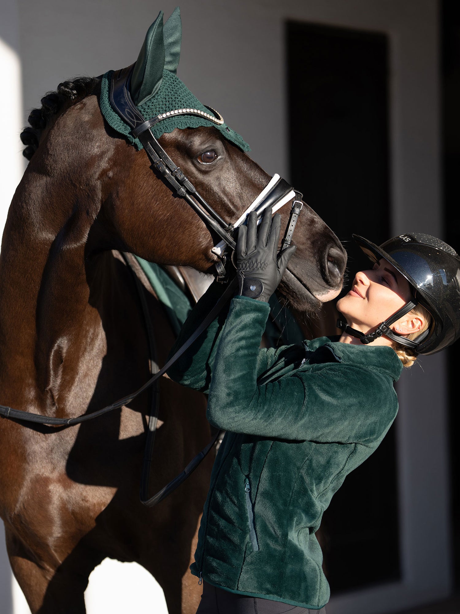 Rider in Equestrian Stockholm Sycamore Green Velvet Fleece Jacket and horse wearing a matching velvet ear bonnet.